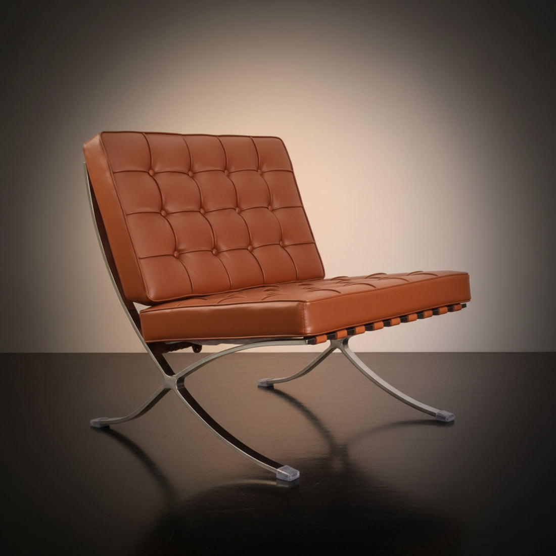 A modern tufted leather chair with a matching ottoman, both in a warm brown color, set on chrome S-curve metal legs 
