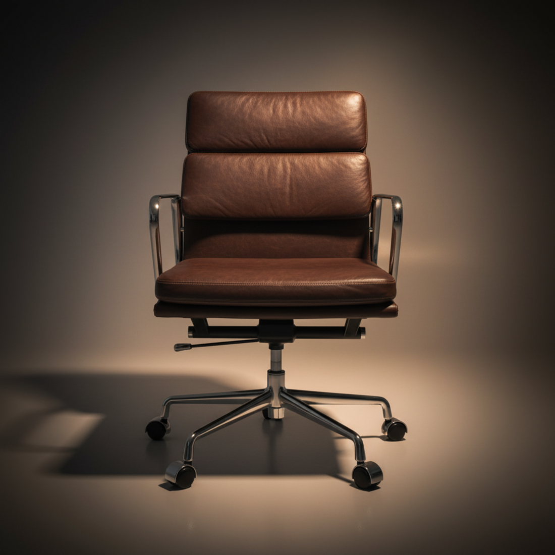 A brown leather office chair with a high back, curved armrests, and a chrome five-star base with casters
