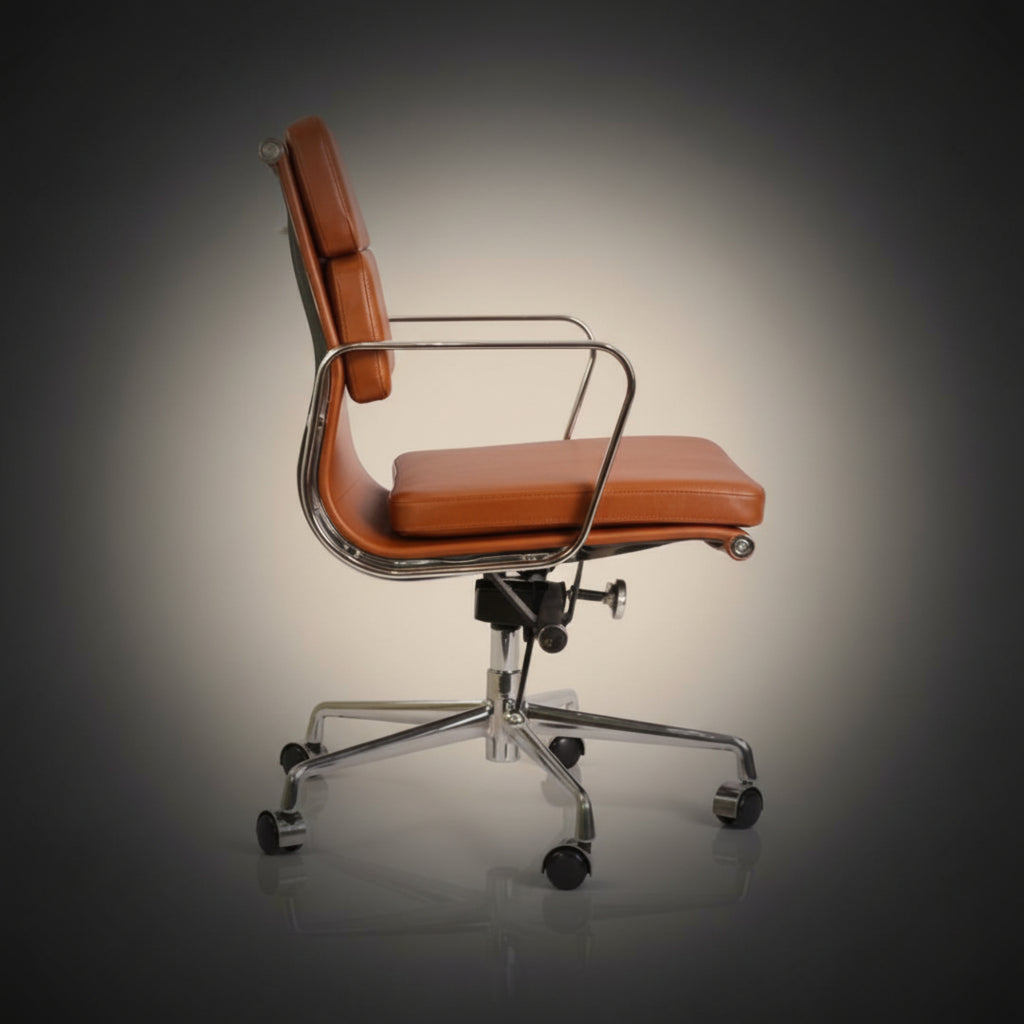 A mid-century modern office chair with orange-brown leather upholstery and a chrome metal frame
