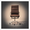 A brown leather office chair with a high segmented backrest, chrome metal armrests and base
