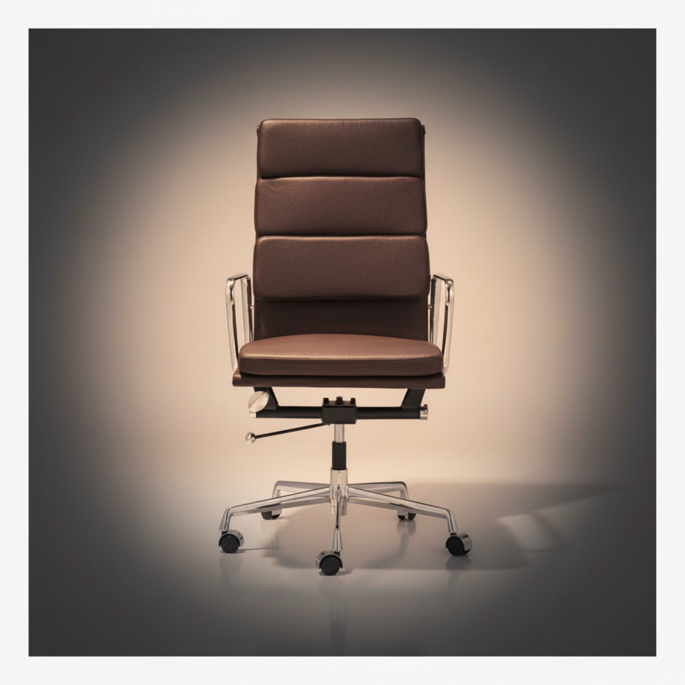 A brown leather office chair with a high segmented backrest, chrome metal armrests and base