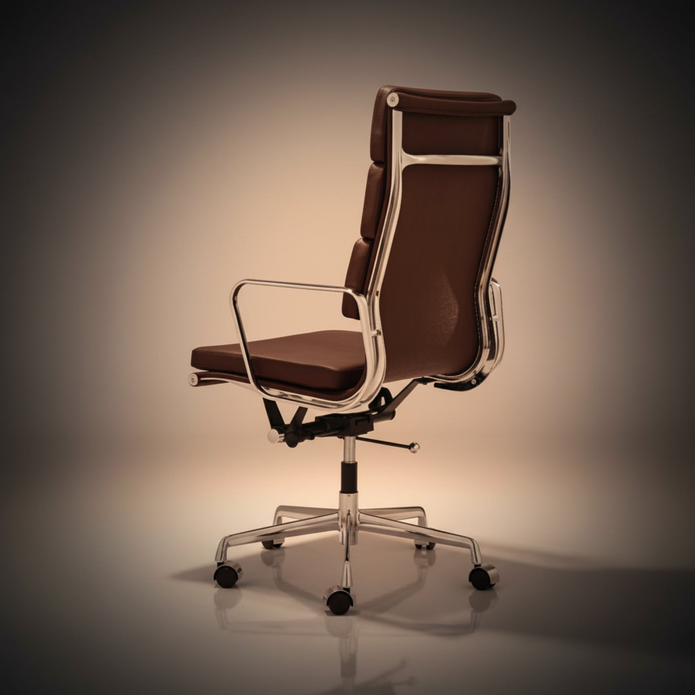 A modern high-back office chair with brown leather upholstery and a polished chrome metal frame, base, and five-wheel casters