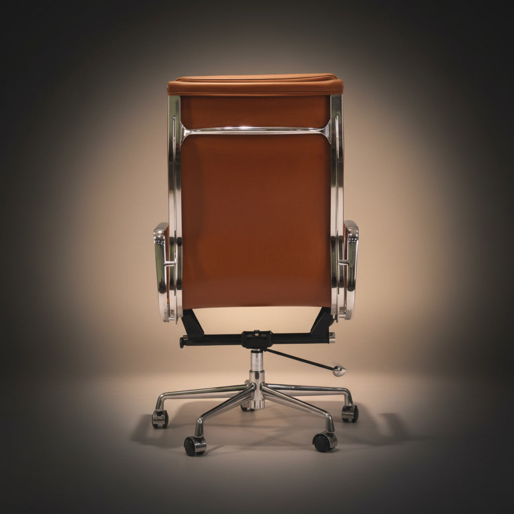 A mid-century modern office chair with a warm brown leather seat and backrest, supported by a polished chrome metal frame.