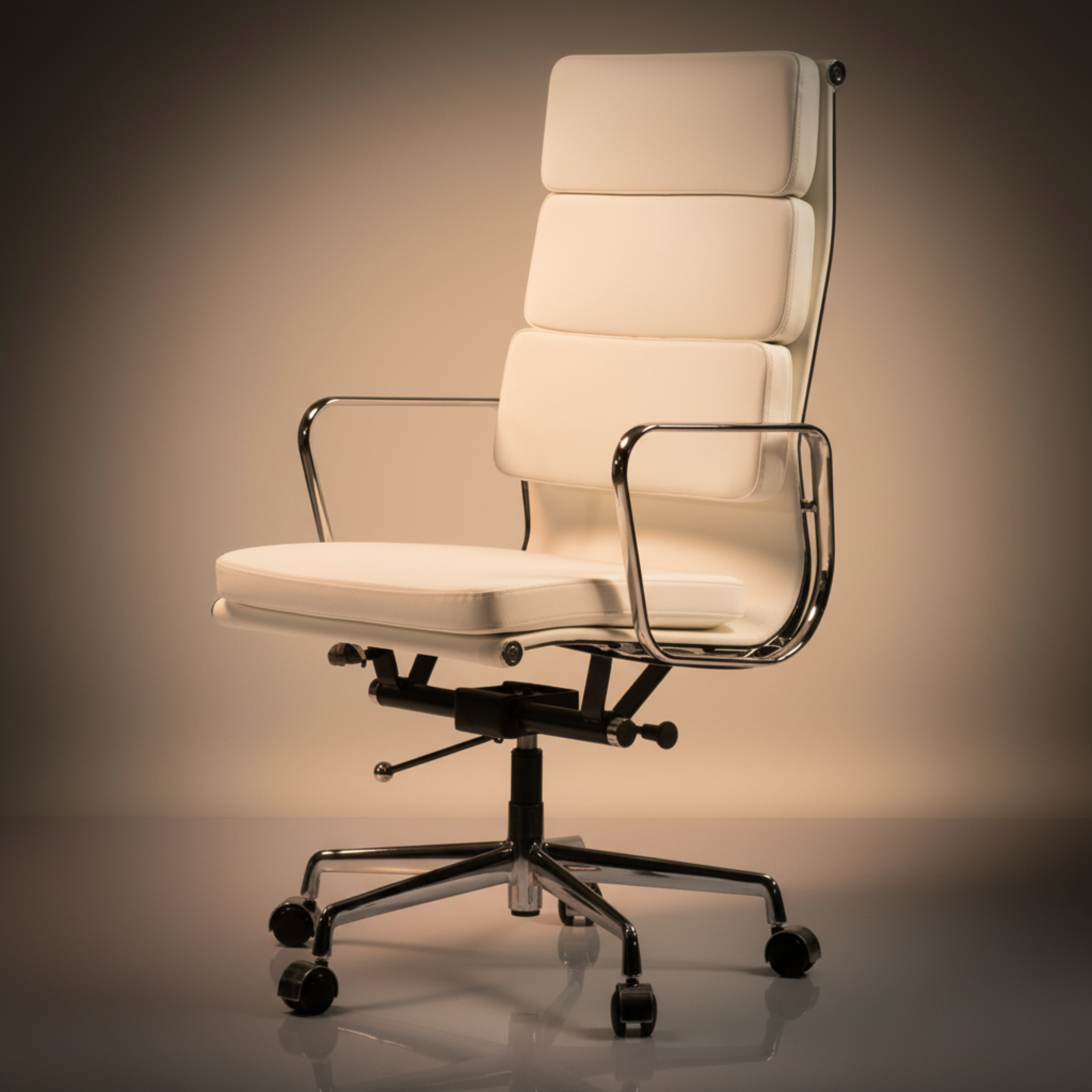 A modern high-back office chair with cream-colored padded upholstery and a polished chrome metal frame, armrests