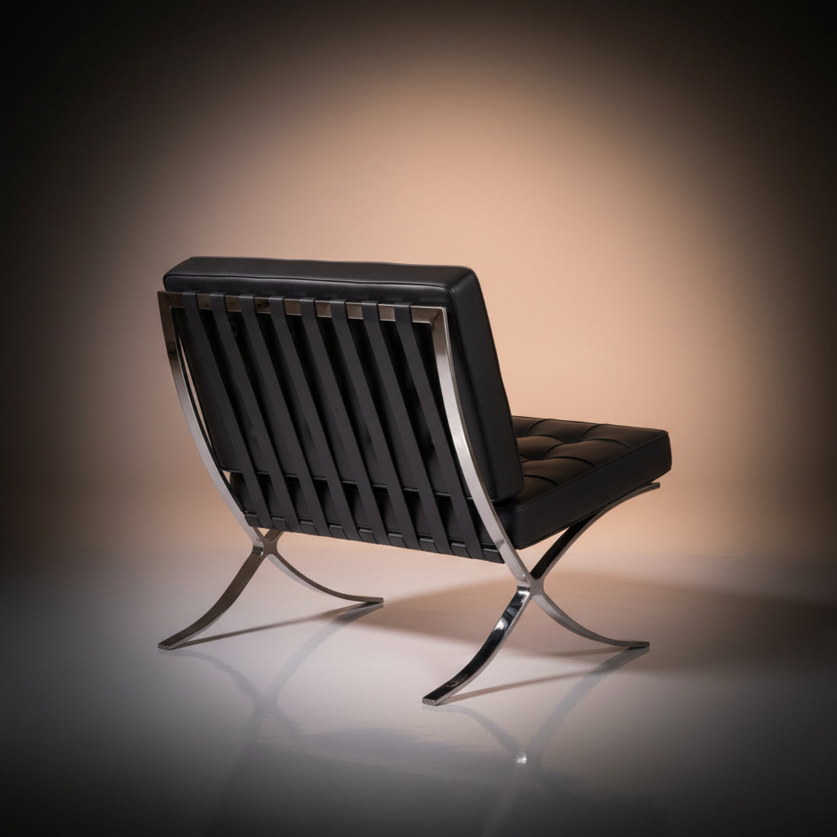 A modern black leather lounge chair with a chrome metal frame and curved legs, photographed on a reflective surface
