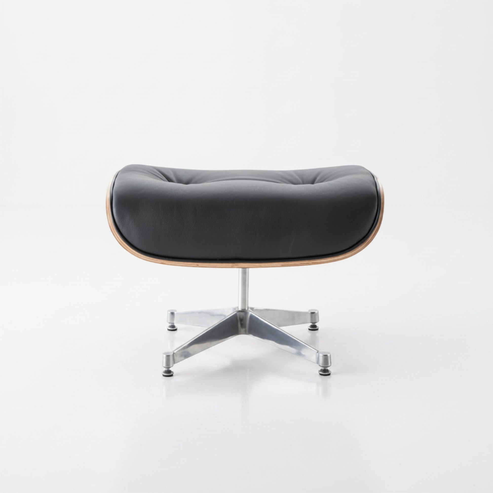A modern lounge chair with a black tufted leather seat cushion, a light natural wood frame