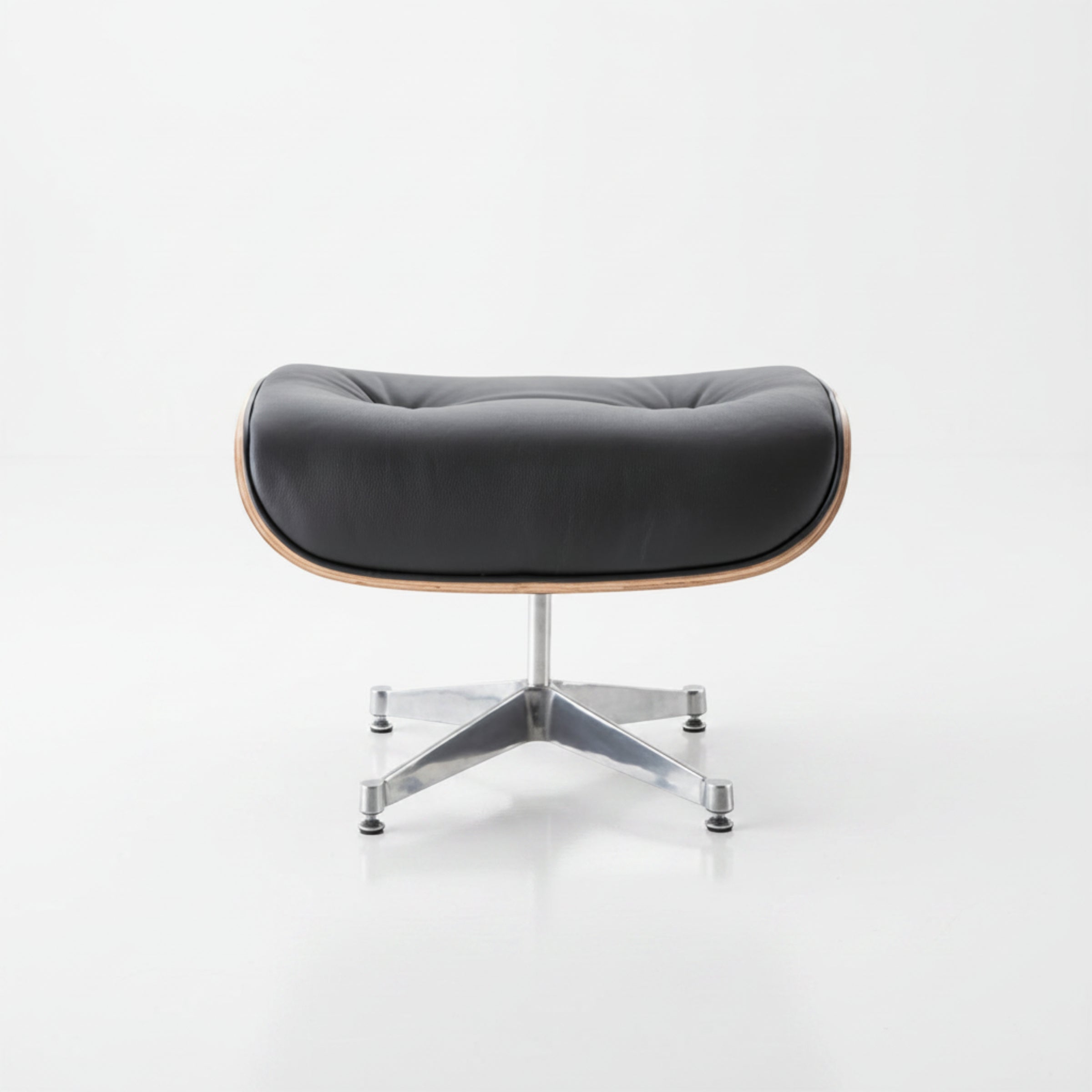 A modern lounge chair with a black tufted leather seat cushion, a light natural wood frame