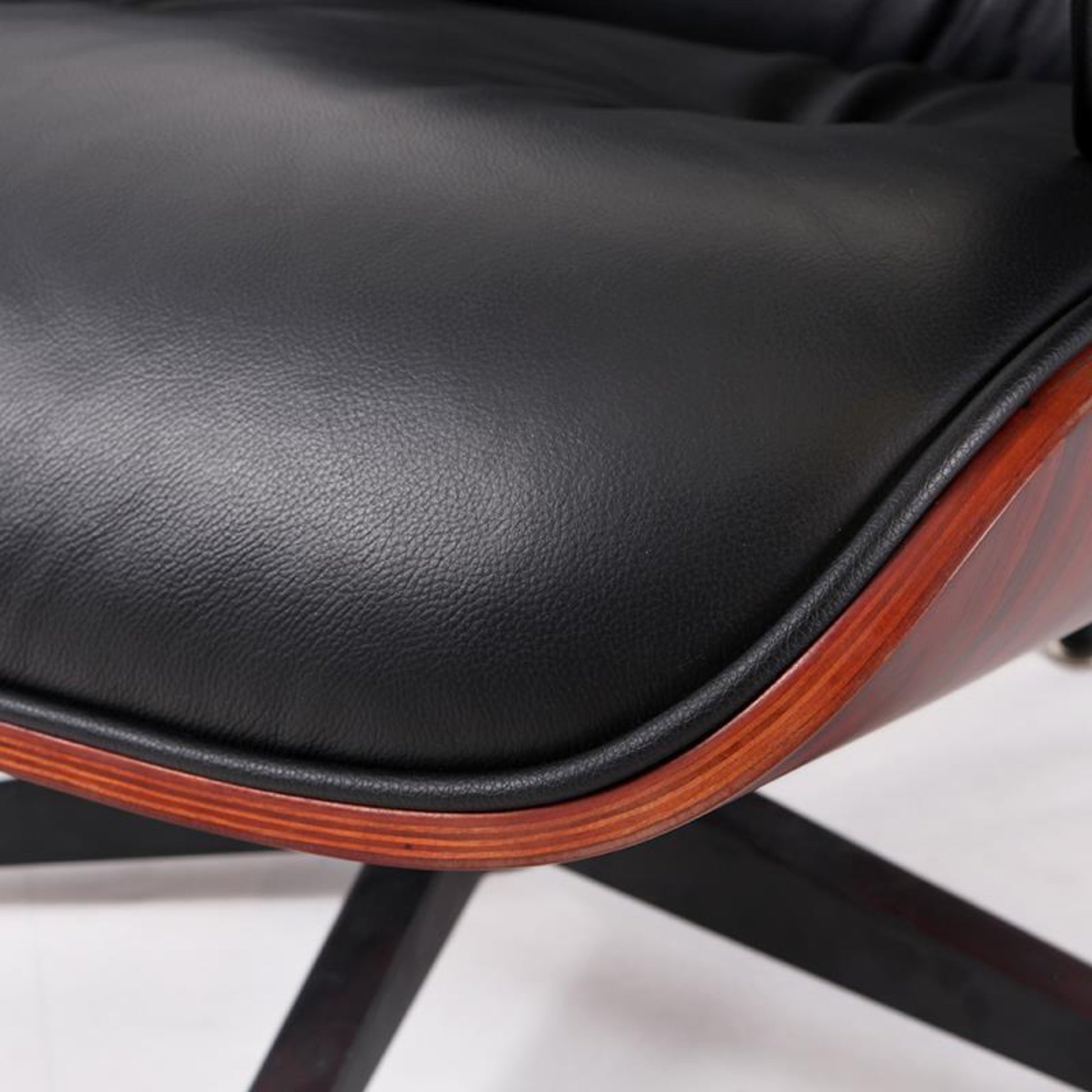 Close-up of a black leather chair seat with wooden trim on a white background