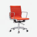 An orange upholstered office chair with a ribbed backrest, chrome metal armrests and base, and black casters, shown on a plain light gray background.