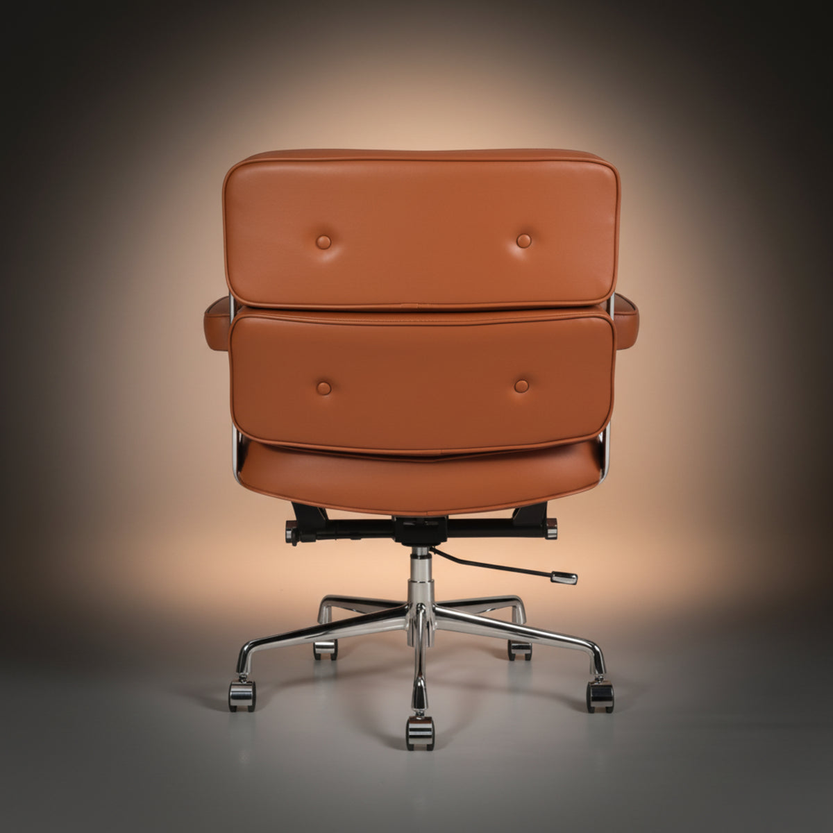 A modern lounge chair with a double tufted backrest upholstered in warm cognac brown leather, featuring chrome-finished metal armrests